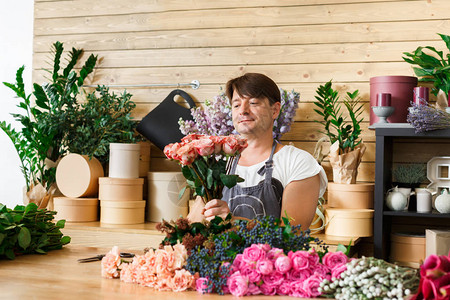 小本生意男花店在花店制作玫瑰花束花艺设计工作室的男助理或老板图片