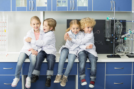 身着实验室大衣的学童坐在化学实验图片