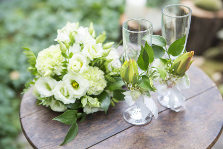在婚礼仪式上用木制桌布着花朵装饰的枯叶玫瑰和玻璃杯图片