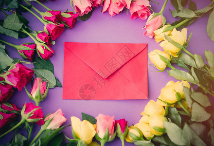 美丽的黄色和粉红玫瑰花朵和信封以紫色背图片