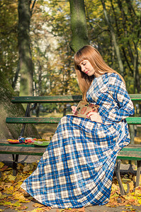 长直发的漂亮女孩穿着蓝色长裙在秋天图片