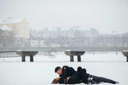 女孩和男孩在公园的雪上躺着图片