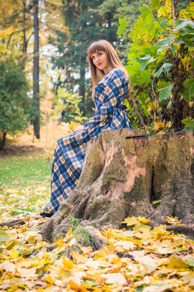 美丽梦幻的姑娘秋天在公园穿蓝色长裙图片