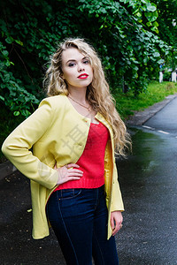 绿色公园装着照相机的金发美女学生穿着黄色夹克红色图片
