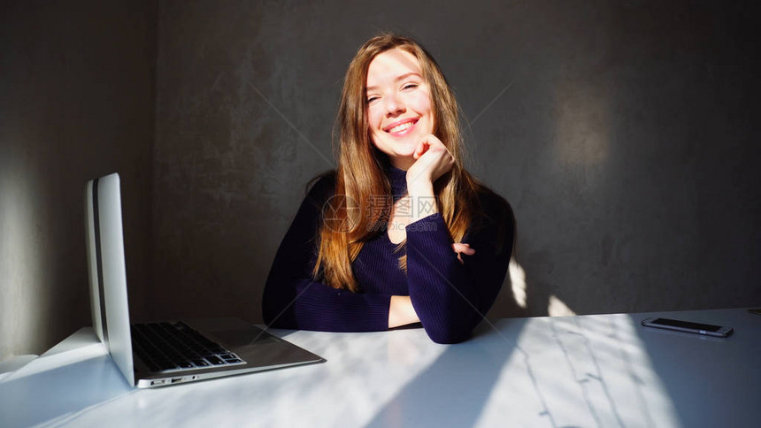 无酒窝的学生坐在桌前微笑着使用笔记本电脑年轻的欧洲高加索女孩有一头长的金发和酒窝成功的概念新的先进技术学图片