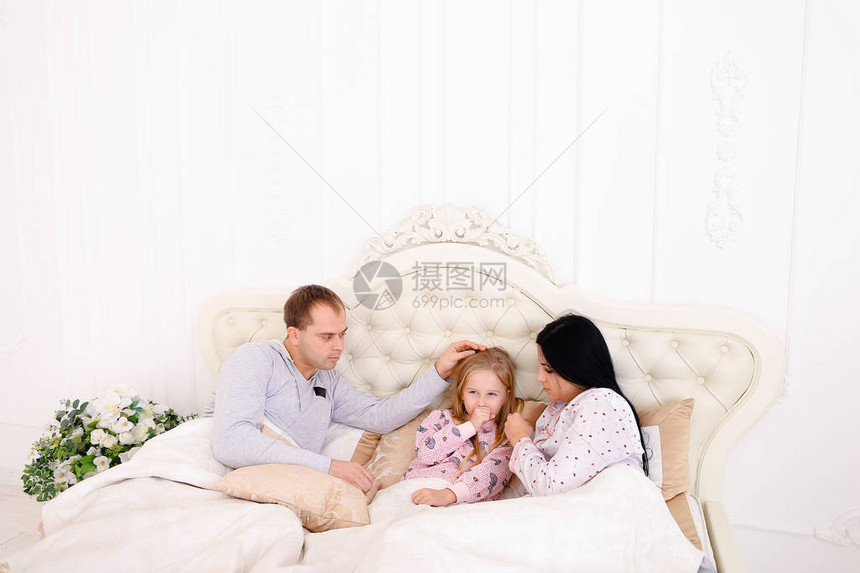 用纸巾擦鼻子孩子和爸妈在床上年轻夫妇照顾他们的女儿长黑发的女人图片