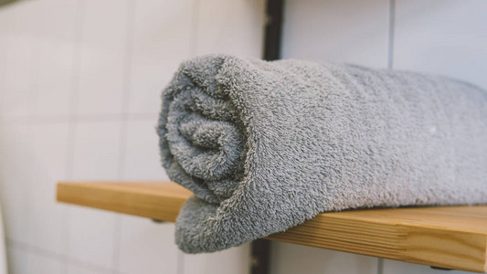 架子上的灰色浴巾特写木架子和卷起来的毛巾浅焦点图片