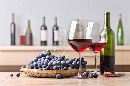厨房桌上的酒瓶和红酒杯一连串蓝葡萄还有厨房陶瓷桌图片
