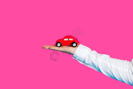 男手握汽车成型玩具在美妙的粉红图片