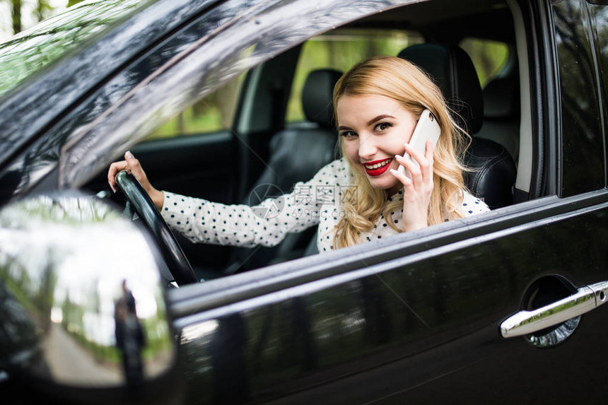 有电话的年轻妇女在驾驶汽车时有电话交图片