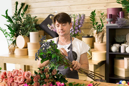 鲜花配送店男花店制作玫瑰花束花艺设计工作室的男助理或老板图片