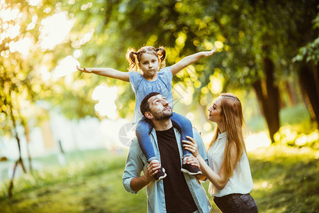 快乐的家庭在秋天夏天在大自然的午后阳光下玩耍母亲父亲和女儿在公园的图片