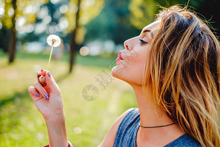 女孩在一个公园吹花朵图片
