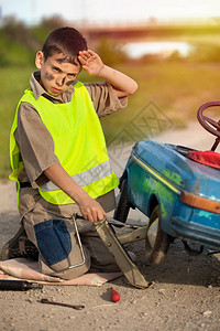 小男孩在旧玩具车上换轮胎背景图片