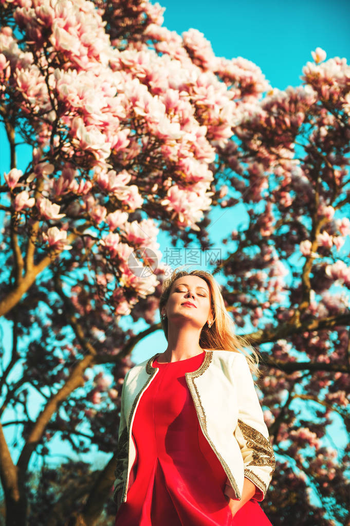 美丽的年轻快乐少女在春天花园享受阳光温暖的一天穿着明亮的红裙图片