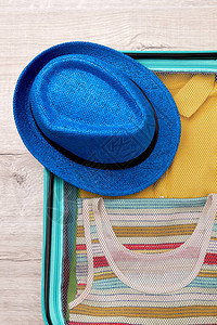 帽子行李箱和旅行衣物衣服装在轮式袋图片