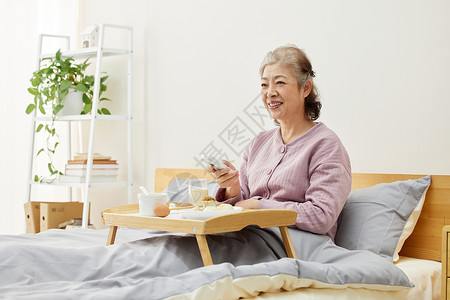 老年奶奶看电视老年人床上吃早餐看电视背景