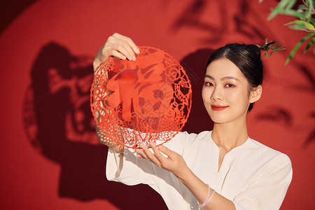 手拿福字窗花的传统青年女性背景图片