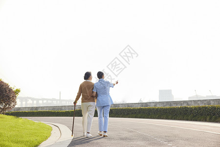 两个老人背影女护工陪伴老人公园散步背影背景