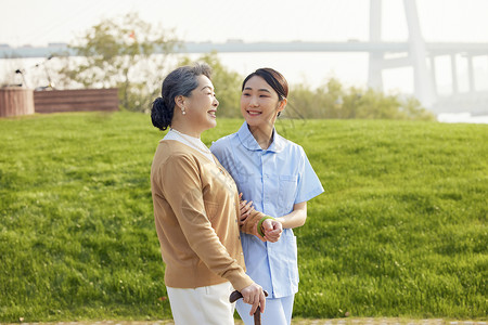 年轻女护工户外陪伴老人散步图片