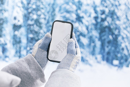 冬日雪地里使用手机特写图片