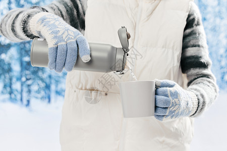 假日装饰雪地里的女子使用保温杯喝水特写背景