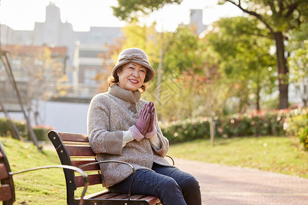 享受冬天中老年妇女坐在公园长椅上休息背景
