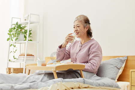 居家老人卧床吃早餐看电视图片