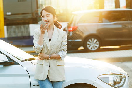 美女语音汽车旁使用手机语音聊天的都市白领背景