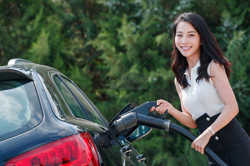 漂亮的青年女人给汽车充电图片