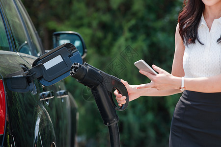 自助功能青年女人使用手机自助充电汽车背景
