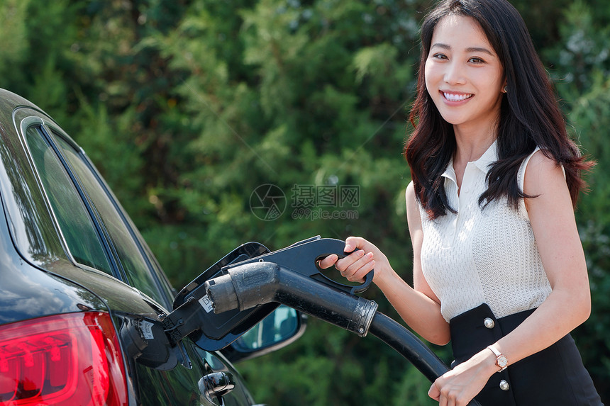 漂亮的青年女人给汽车充电图片