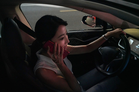 夜晚驾驶汽车的青年女人打电话图片