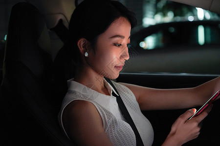 夜晚青年女人坐在汽车里使用手机图片