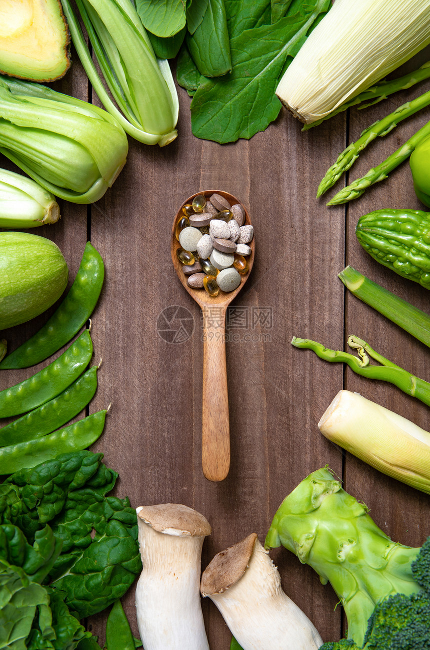 绿色果蔬和木匙上的多色药品图片