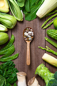 绿色安全食品绿色果蔬和木匙上的多色药品背景