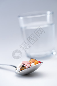 水杯和匙上的多色药丸背景图片