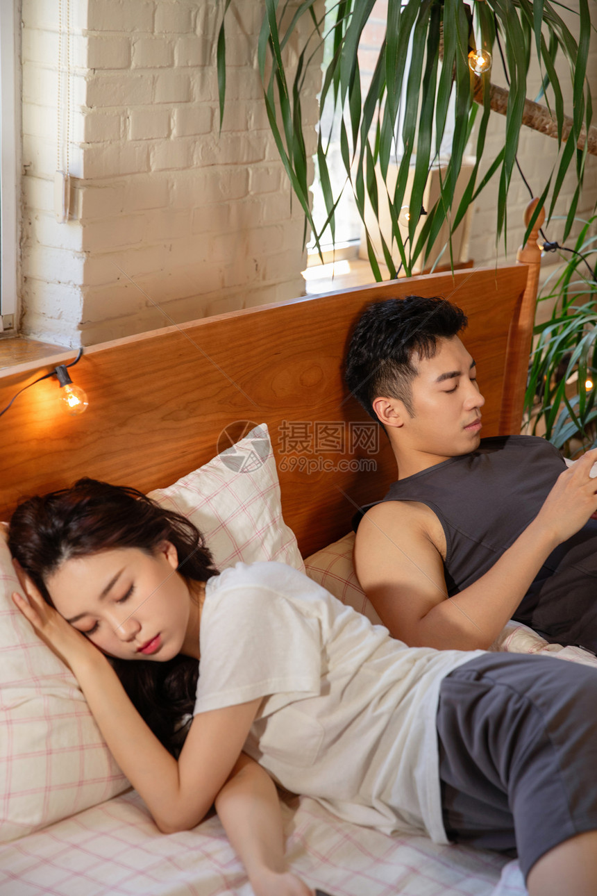 青年夫妇坐在床上生闷气图片