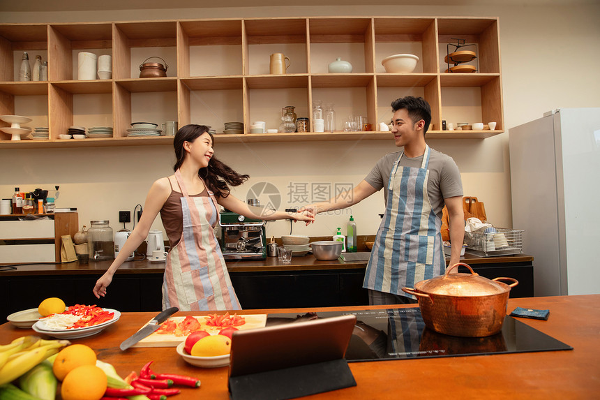青年夫妇在家边做饭边跳舞图片
