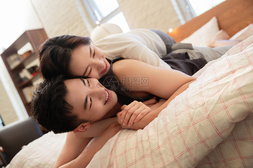 青年情侣趴在床上聊天图片