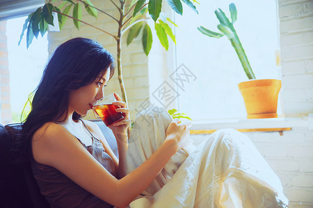 斜靠年轻女人在家喝茶休息背景