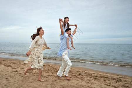 抱起来一家三口在海边玩耍背景