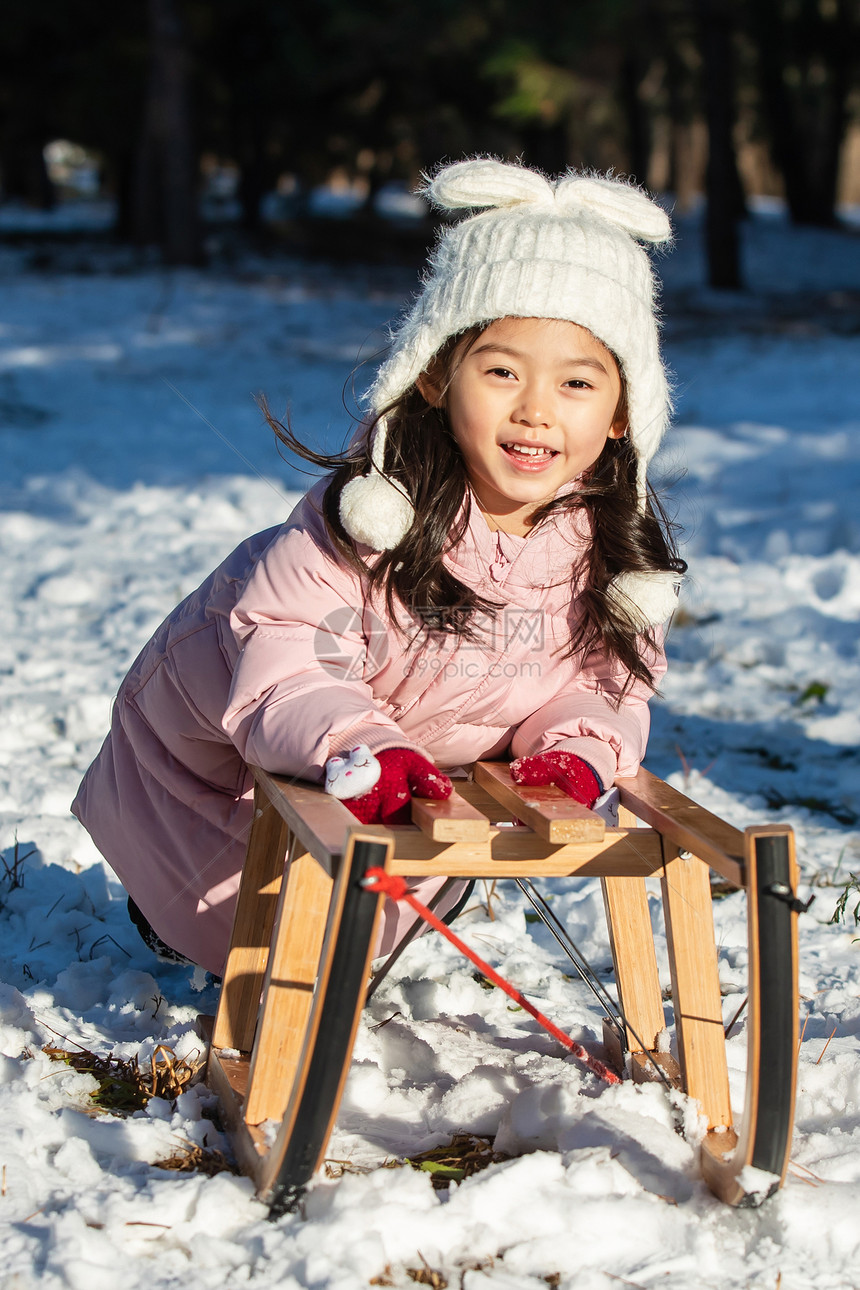 快乐的小女孩在雪地上玩雪橇图片
