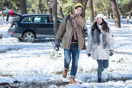 雪中漫步的情侣冬季年轻夫妇自驾游背景