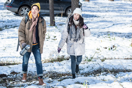 雪中漫步的情侣冬季年轻夫妇自驾游背景