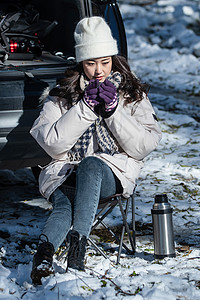 坐在汽车旁喝热水的青年女人高清图片