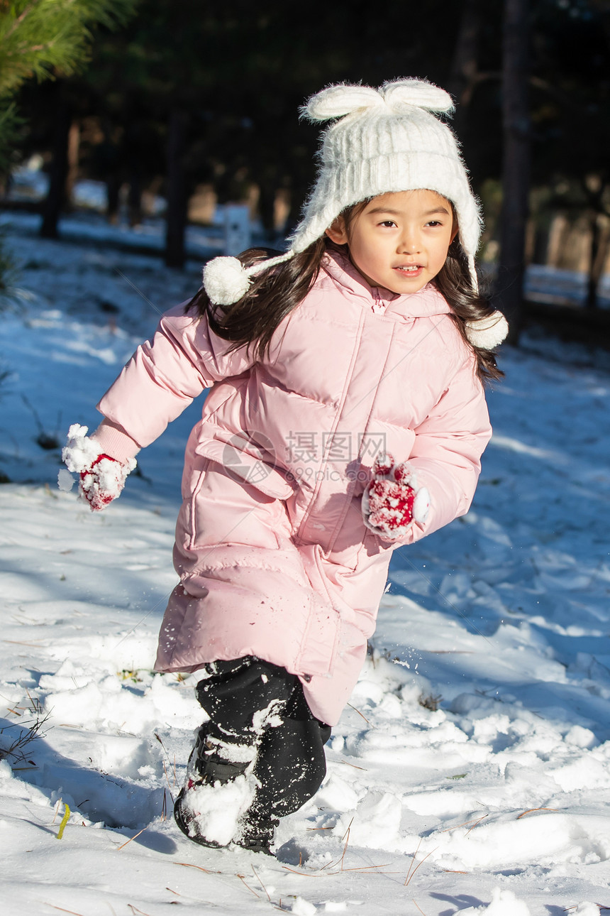 快乐的小女孩在雪地里玩耍图片
