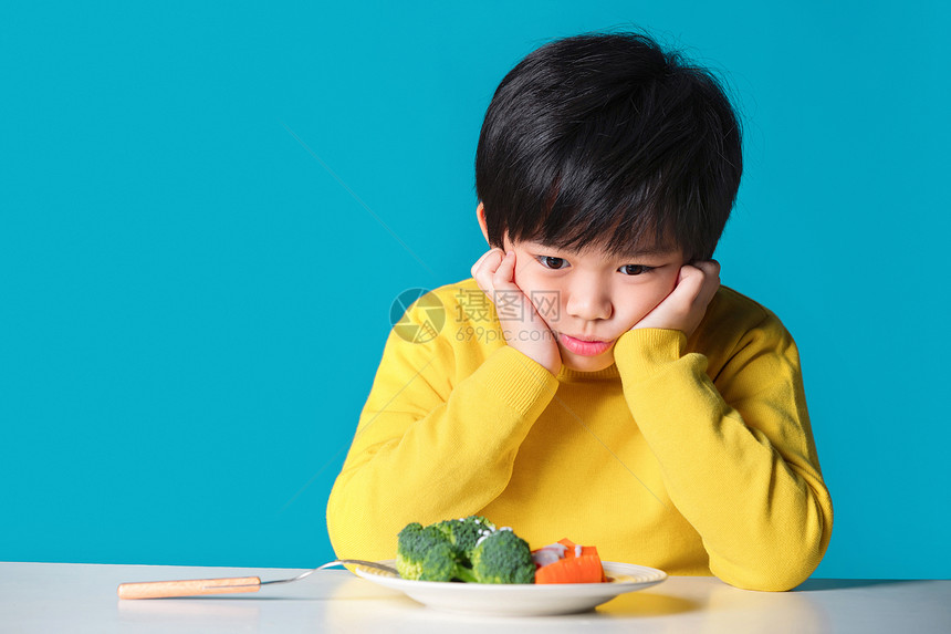 盯着蔬菜发愁的小男孩图片