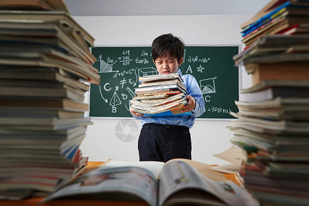 站着看书的男孩搬着沉重课本的小学男生背景