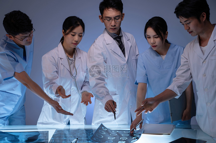 医务工作者用手指着X光片讨论研究图片